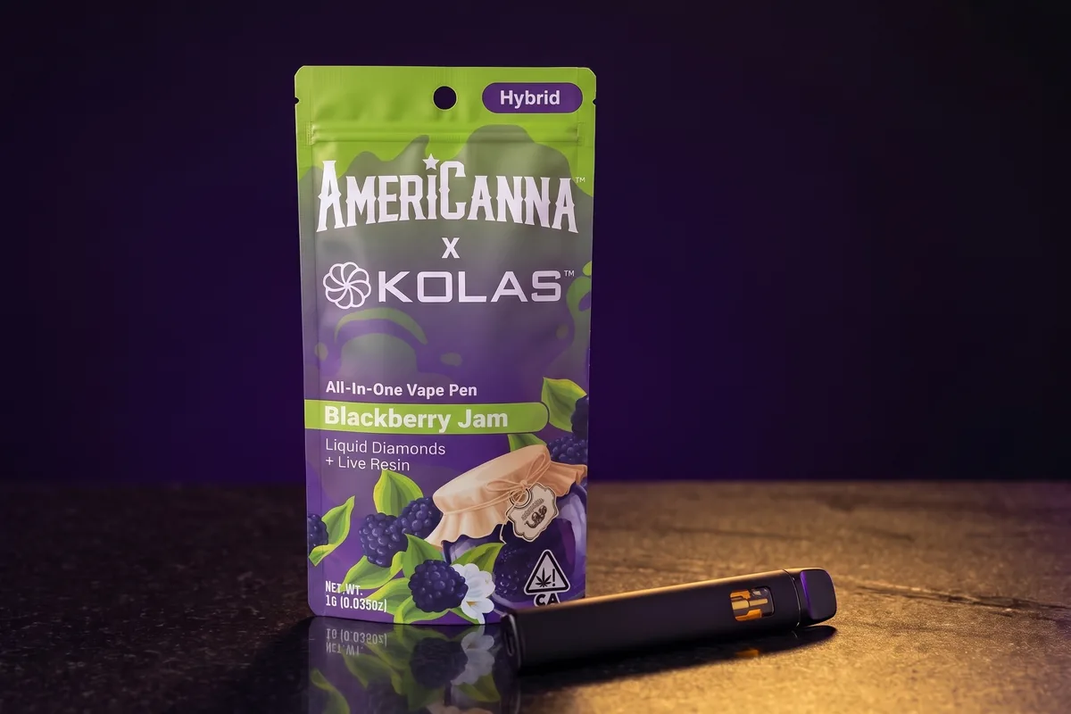 An AmeriCanna x KOLAS Blackberry Jam all-in-one vape pouch, lime green and purple with a Hybrid label, and a black vape pen in front of it.