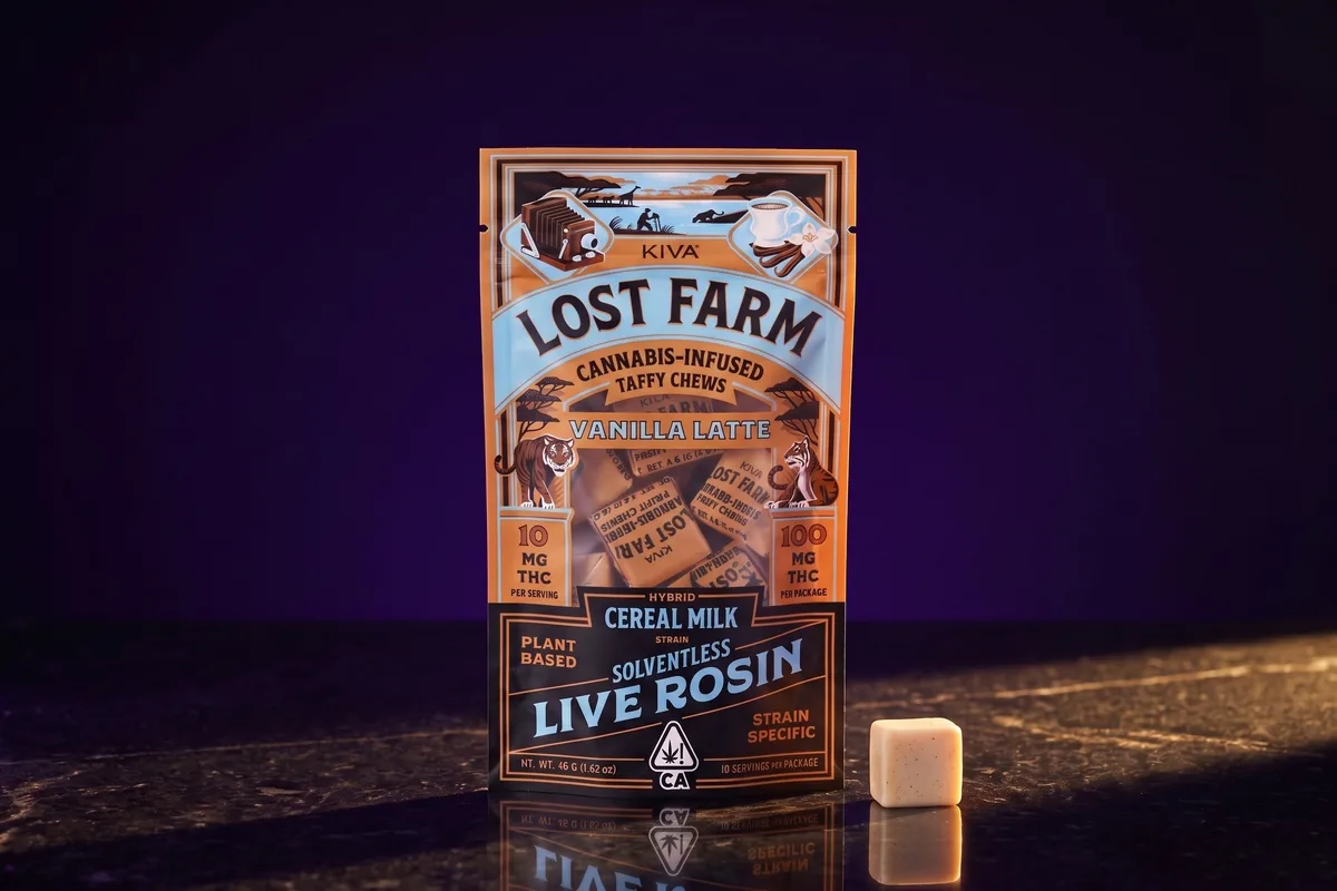 A Kiva Lost Farm Vanilla Latte chews pouch, 10 mg THC per serving, with one unwrapped chew in front, on black stone in gold light.