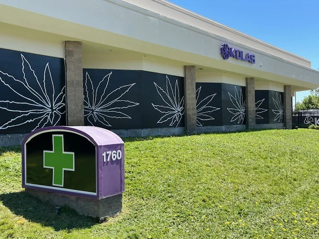 The purple 1760 monument sign with a green cross on the lawn in front of the shop