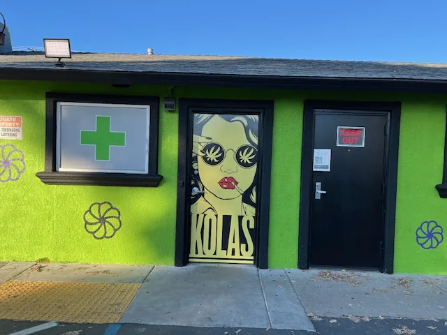 The entrance at KOLAS Main Ave: a lime green wall, a green cross window and the KOLAS door mural